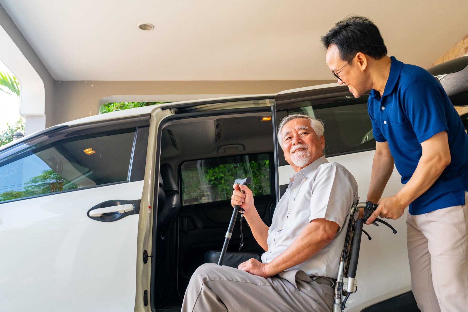 Caregiver helping senior man get in the car.